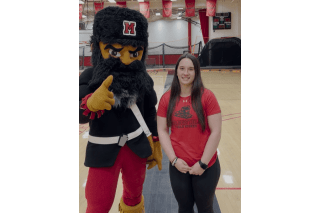 A girl standing next to a mountaineer. 