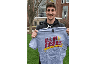 A man standing with a T-shirt that says Huskies All In. 