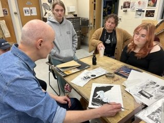 A group of people sitting together looking at art. 