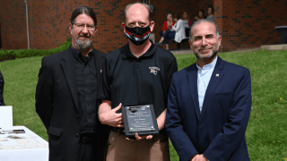 Three people standing next to each other with an award. 