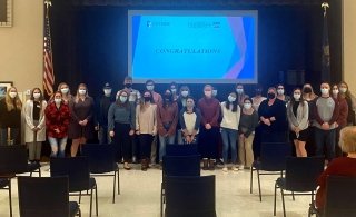 A group of people standing by a projector. 