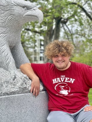 Jaren Tilford sitting in front of an eagle statue. 