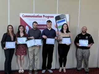 A group of people standing side by side with awards. 