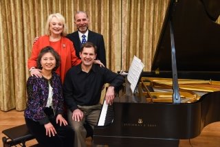 A group of people sitting next to a piano. 