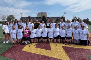 Members and alumni of the Field Hockey Team pose for a group photo on the field.