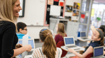 A teacher overlooking her students working. 