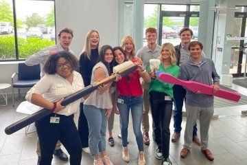 A group standing with two large toothbrushes. 