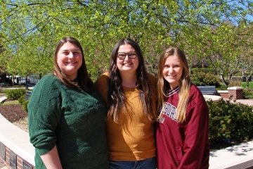 A group of three, standing side by side. 