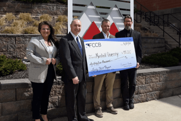 A group of four holding a large check. 