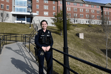 A female officer standing in front of Mansfield University. 