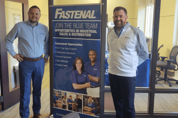 Two men standing next to a fastneal sign. 