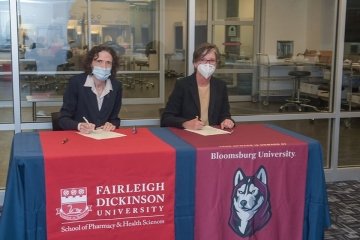 Two people sitting behind a signing table. 