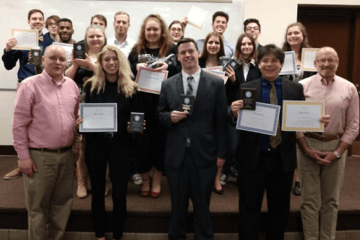 A group standing together with awards. 