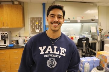 Manuel Gutierrez wearing a Yale crewneck in a lab environment. 