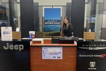 Student pictured behind the desk of Brown-Daub Dealerships
