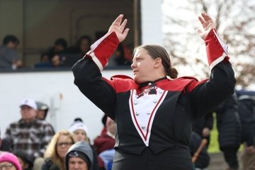 Kaycee Hulslander in marching band attire outside pictured with a group of onlookers. 