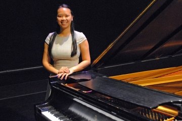 A woman standing with a piano.