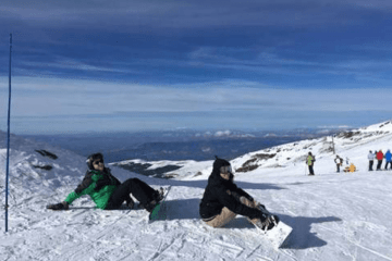 Two people sitting in the snow. 