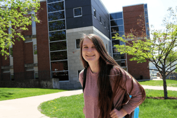 A girl standing in front of the school. 