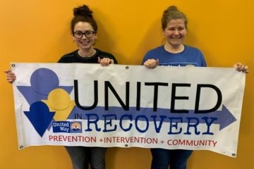 Two girls holding United Recovery sign.