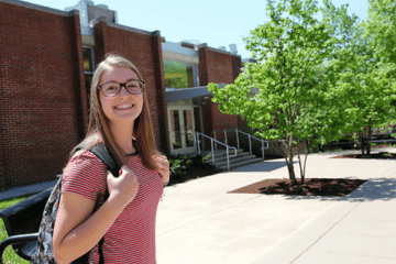 A girl standing in front of the school. 