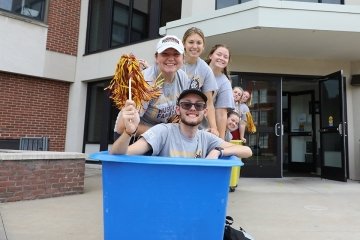 One person in a move in bin, people behind pushing the bin.