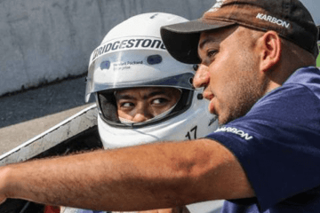 A man in a helmet with another man coaching him. 