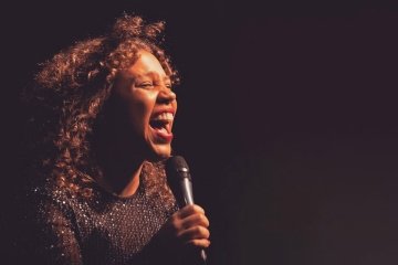 A close up image of a girl singing, holding a microphone. 