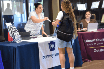 Vendor handing a student a card at a Pennsylvania Vendor table. 