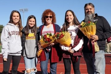 A group standing side by side with flowers. 