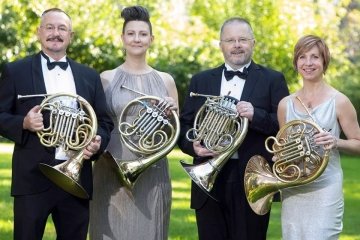 Two men and two women pictured holding French horns. 
