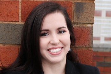 A headshot of a woman standing against a brick building. 