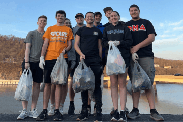 Students holding grocery bags of trash.