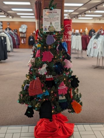 A Christmas tree with hats and gloves on it. 