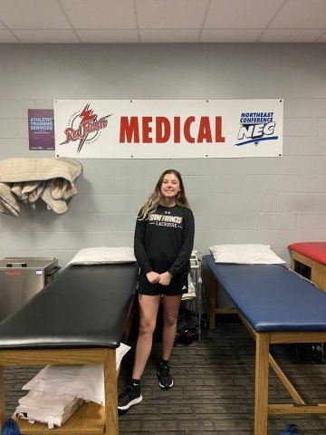 Taylor Johns standing between to medical (chiropractic) beds. 