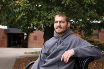 A man leaning back on a bench outside. 