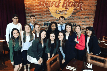 A group of people standing together in front of a brick wall. 