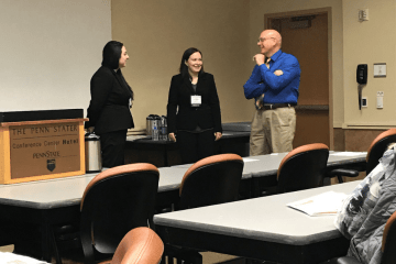 Three people talking to each other in a classroom. 