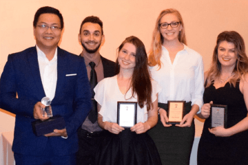 A group of people standing together with awards. 