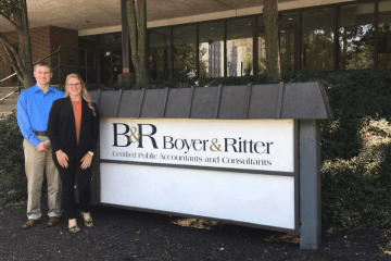 Two people standing next to a B&R sign.