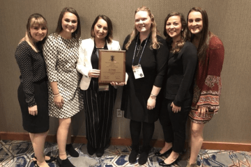 A group of people standing together with an award. 