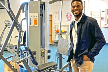 A man standing next to gym equipment. 