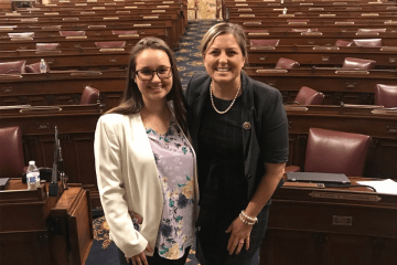 Two people standing side by side in an auditorium. 