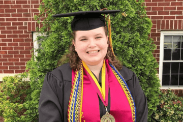 A headshot of a woman in her graduation cap and gown. 