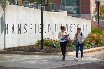 Two students walking by the Mansfield wall. 