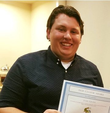 A man smiling with an award. 