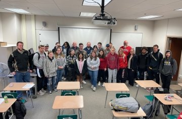 A group of students standing at the front of a classroom for a photo. 