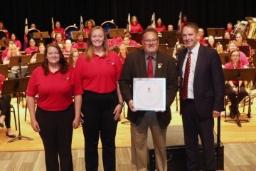 The marching band standing with an award. 