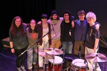 A group of people standing behind a drum set. 