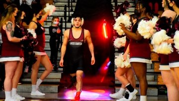 A wrestler walking out between cheerleaders. 